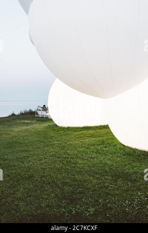 Vertikale Aufnahme von mehreren großen Ballonen auf einer grünen Landschaft Stockfoto