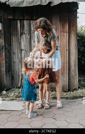 Eine Gastgeberin kümmert sich mit ihren Töchtern auf ihrem Hof um die neu geborenen gelben Hühner. Landwirtschaft zu Hause Stockfoto