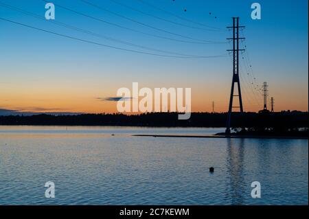 Silhouetten von hohen Pfosten gegen bunten Himmel während des Sonnenuntergangs. Stockfoto