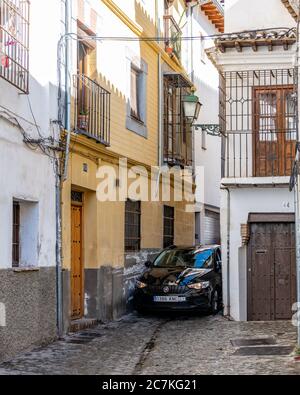 Enger Druck. In der Calle de San Juan de los Reyes in Granadas historischem maurischen Viertel Albaicin quetscht sich kaum ein kleines Auto zwischen den Gebäuden. Stockfoto