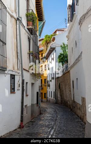 Die schmale, gewundene Gasse und die hohen weiß getünchten Gebäude sind typisch für Granadas historisches maurisches Viertel Albaicon Stockfoto