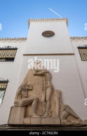 Eine Skulptur eines Mönchs, der in den Himmel blickt, während ein Flugzeug über der Seniorenresidenz San Juan de Dios im Albaicin-Viertel von Granada fliegt. Stockfoto