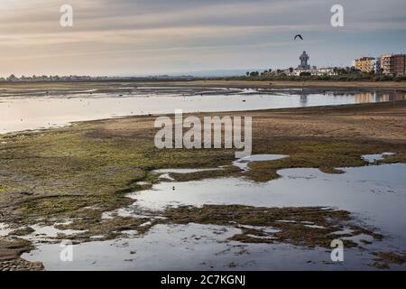 Panoramablick auf den Strand von La Gaviota bei Ebbe mit dem Leuchtturm von Isla Cristina im Hintergrund. Existiert in: Huelva, Andalusien, Spanien Stockfoto