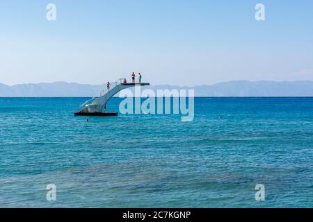 RHODOS, GRIECHENLAND - 13. Mai 2018: Menschen auf einer Tauchplattform. Elli Strand, der Hauptstrand von Rhodos Stadt. Griechenland Stockfoto