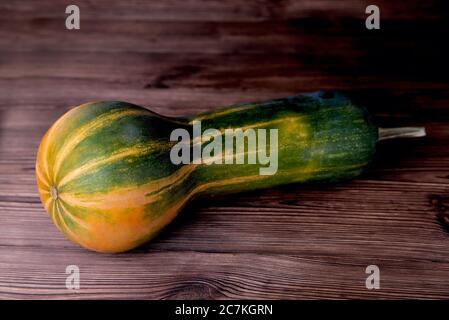 Gelb-grüner länglicher Kürbis, natürlicher Holzhintergrund, Diätnahrung, Halloween Nahaufnahme Stockfoto