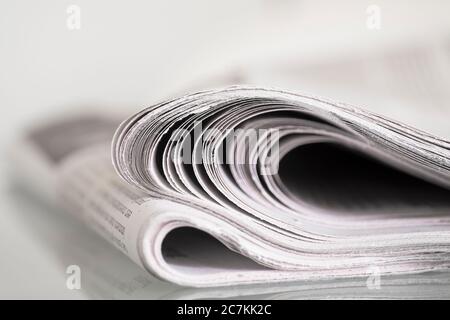 Gefaltete Zeitung auf einem Tisch vor einfachem Hintergrund mit enger Schärfentiefe Stockfoto