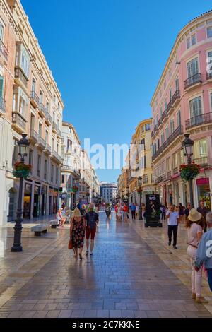 Vertikale Aufnahme der wunderschönen Einkaufsstraße in malaga mit Einheimischen und Touristen, die die beeindruckenden architektonischen Gebäude erkunden. Stockfoto