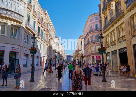 Horizontale Aufnahme der wunderschönen Einkaufsstraße in malaga mit Einheimischen und Touristen, die die beeindruckenden architektonischen Gebäude erkunden. Stockfoto