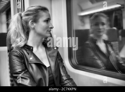 Frau ohne Gesichtsmaske, sitzt im Zug, reflektiert im S-Bahn-Fenster, Corona-Krise, Stuttgart, Baden-Württemberg, Deutschland