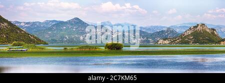 Herrlicher Blick auf den Skadar See, umgeben von grünen Berggipfeln an einem sonnigen Tag. Lage: Nationalpark Skadarsee, Montenegro, Balkan, Europa. Stockfoto