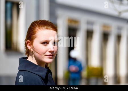 Junges Mädchen mit rötlichen Haaren lächelt auf Kamera-Porträt, außen, Seitenansicht Stockfoto