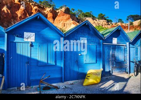 Europa, Portugal, Algarve, Litoral, Barlavento, Bezirk Faro, bei Albufeira, Praia dos Olhos de Agua, blaue Fischerhütten vor rotbraunen Klippen Stockfoto