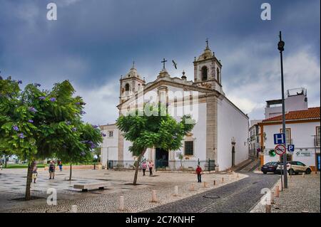 Europa, Portugal, Algarve, Litoral, Barlavento, Felsalgarve, Faro District, Lagos, Praca do Infante Dom Henrique, Igreja de Santa Maria Kirche, ehemalige Ruhestätte von Heinrich dem Seefahrer, blühende Jacaranda Bäume Stockfoto