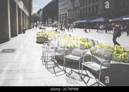 Stühle und Blumen in der Fußgängerzone in München, Bayern, Deutschland Stockfoto