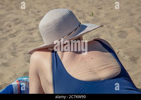 Eine ältere Frau, in einem Sommerhut am Strand. Modellrückseiten. Sonniger Sommertag am Meer. Konzept: Gesunder Lebensstil, Entspannung. Hochwertige Fotos Stockfoto