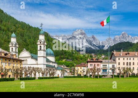 Das Zentrum von Agordo mit der Kirche mit zwei Glockentürmen und der großen grünen Wiese namens "broi", agordino, belluno, venetien, italien Stockfoto