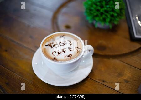 High-Angle-Aufnahme von Kaffee mit den Worten Togo Cafe Und die Herzen darauf legen auf den hölzernen Tisch Stockfoto