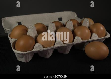 Eierschale mit Hühnereiern und dekorativem Hase auf grau und schwarz. Auf einem Holzbrett Stockfoto