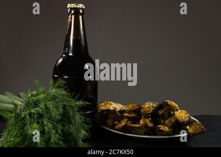 Eine Flasche dunkles Bier und ein Teller Fisch. Auf einem dunklen Hintergrund. Stockfoto