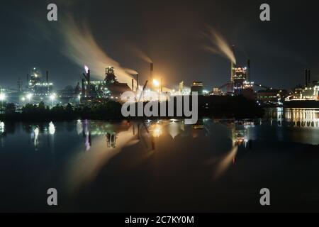 Die breite Aufnahme des industriellen Teils der Stadt in der Nähe Das tiefblaue Meer in der Nacht Stockfoto