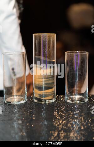 Nahaufnahme von Sandkunst mit schwarzen und gelben Schichten In einem Glas Stockfoto