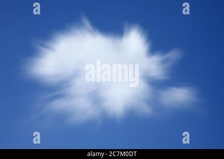 Hintergrundstruktur einer einzigen flauschigen Cumulus Wolke in einem blauen klaren Himmel mit einem Zoom Burst Streifen Unschärfe-Effekt Stock Foto Stockfoto