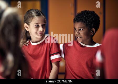 Fußballspieler vor dem Training.lächelnde Mädchen und Jungen Freunde vor dem Training in Umkleideraum. Stockfoto