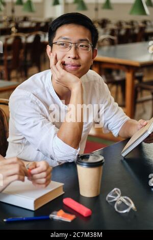 Junge attraktive asiatische Student in Brillen traumhaft studieren in der Bibliothek der Universität Stockfoto