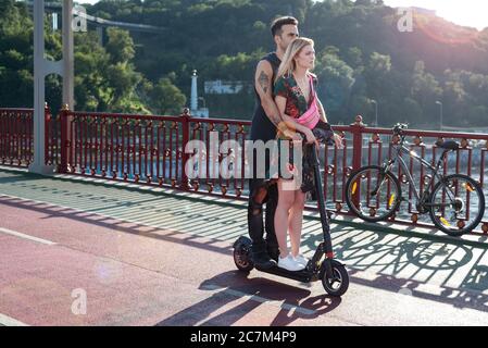 Kiew, Ukraine - 11. Juli 2020. Fußgängerbrücke. Junge attraktive Paar in der Liebe Reiten ein elektrisches einrad zusammen genießen Sommertag Stockfoto