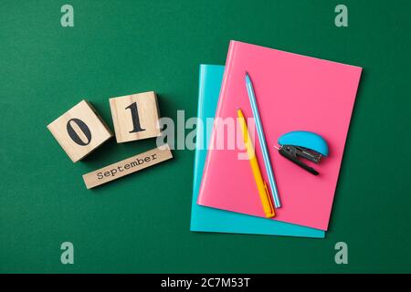 Holzkalender mit 1. september und Schulbedarf auf grünem Hintergrund Stockfoto