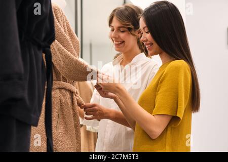 Zwei fröhliche stilvolle Mädchen glücklich Wahl Kleidung im Mode-Shop Stockfoto