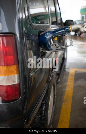 Vertikale Aufnahme einer Benzindüse in einer Tankstelle Füllen Sie den Kraftstofftank des Fahrzeugs auf Stockfoto