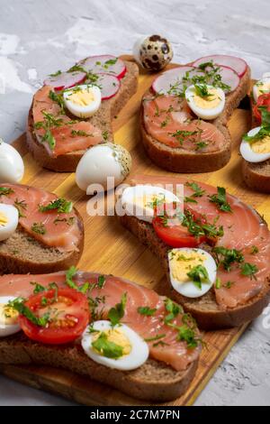 Sechs Wachtelsandwiches zum Frühstück. Holzschneidebrett, Nahaufnahme Stockfoto