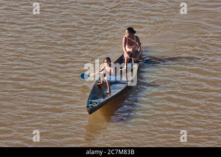 Eine Mutter und ihre Tochter paddeln auf dem Amazonas in der Nähe von Belem in para State, Brasilien, mit einem offenen Holzkanu. Stockfoto