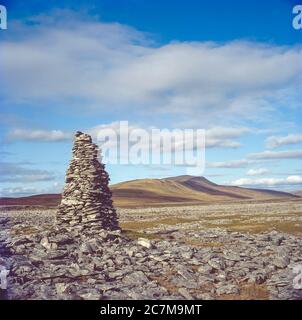 Dies ist eines von mehreren künstlichen steinhaufen, die auf dem Twistleton Scar Moor gebaut wurden, um die Navigation über das Moor bei widrigen Wetterbedingungen zu unterstützen, um Männern beim Spazierengehen zwischen Dörfern im 18. Jahrhundert zu helfen. Während des Baus des Ribblehead Viadukts, das hier in Richtung Whernside gesehen wurde, wurde im Frühjahr 2000 ein Yorkshire Dales Three Peaks of Ingleborough, Whernside und Penyghent errichtet. Stockfoto