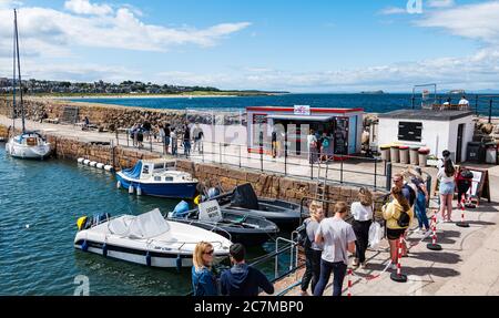 North Berwick, East Lothian, Schottland, Großbritannien, 18. Juli 2020. UK Wetter: Sommersonne in einer sehr belebten Küstenstadt, die wieder normal ist, wenn auch mit sozialen Distanzierungsmaßnahmen. Die beliebte Lobster Shack hat eine lange gesellschaftlich distanzierte Schlange um den Hafen Stockfoto