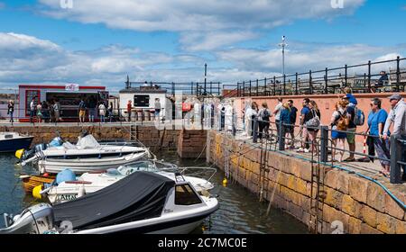 North Berwick, East Lothian, Schottland, Großbritannien, 18. Juli 2020. UK Wetter: Sommersonne in einer sehr belebten Küstenstadt, die wieder normal ist, wenn auch mit sozialen Distanzierungsmaßnahmen. Die beliebte Lobster Shack hat eine lange gesellschaftlich distanzierte Schlange um den Hafen Stockfoto