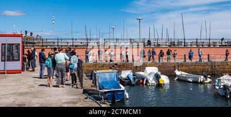 North Berwick, East Lothian, Schottland, Großbritannien, 18. Juli 2020. UK Wetter: Sommersonne in einer sehr belebten Küstenstadt, die wieder normal ist, wenn auch mit sozialen Distanzierungsmaßnahmen. Die beliebte Lobster Shack hat eine lange gesellschaftlich distanzierte Schlange um den Hafen Stockfoto