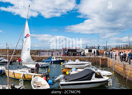 North Berwick, East Lothian, Schottland, Großbritannien, 18. Juli 2020. UK Wetter: Sommersonne in einer sehr belebten Küstenstadt, die wieder normal ist, wenn auch mit sozialen Distanzierungsmaßnahmen. Die beliebte Lobster Shack hat eine lange gesellschaftlich distanzierte Schlange um den Hafen Stockfoto