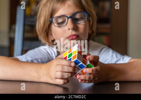 Kind mit Brille versucht, den Rubik-Würfel zu lösen Stockfoto