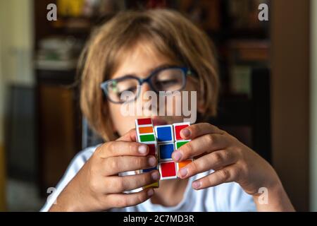 Kind mit Brille versucht, den Rubik-Würfel zu lösen Stockfoto