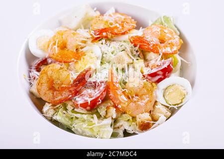 Caesar Salat mit gebratenen Garnelen und Parmesan auf einem weißen Teller. Nahaufnahme. Stockfoto