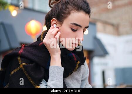 Portrait von pensive Brünette Mädchen Musik in drahtlosen Ohrhörern hören Stockfoto