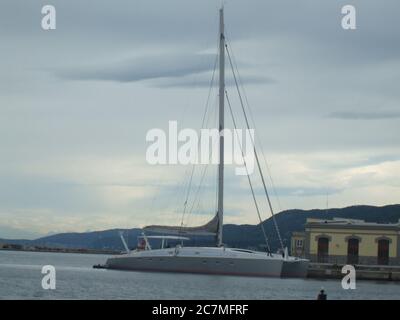 Schöne Aufnahme eines schwimmenden Segelbootes an einem Hafen Ein wolkiger Tag Stockfoto