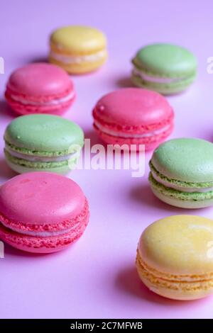 Bunte Makronen auf pastellfarbenem Hintergrund von oben. Vertikales Foto Stockfoto