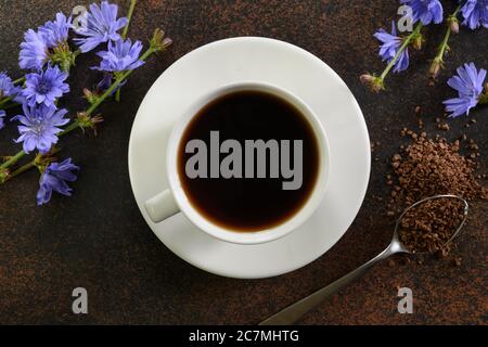 Nützliches Chicorée Getränk und blaue Blumen auf braun. Gesundes Kräutergetränk, Kaffee-Ersatz. Draufsicht. Nahaufnahme. Stockfoto