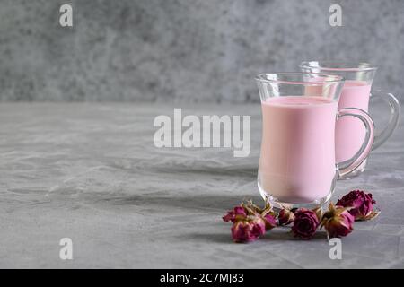 Rose Mond Milch und trockene Rosen auf grauem Hintergrund. Speicherplatz kopieren. Stockfoto