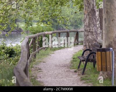 Naturlehrpfad mit Geländer und einer Holzbank, neben einem Fluss Stockfoto