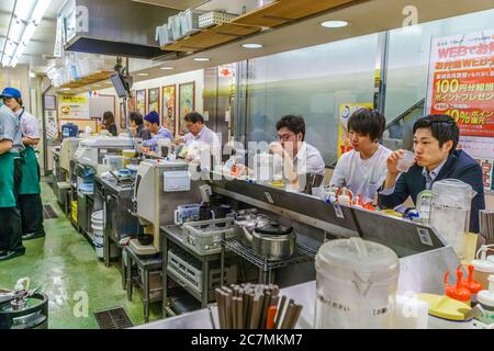 Tokio/Japan - 15. September 2018: Japanische Salarymen sitzen am Tresen im Ramen-Laden und essen ein schnelles Frühstück, bevor sie bei Büroarbeiten arbeiten gehen. Stockfoto