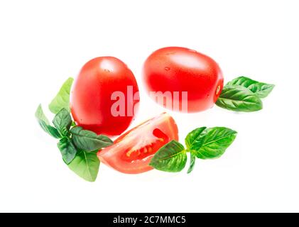Tomaten mit grünen Basilikumblättern auf weißem Hintergrund isolieren. Platz kopieren, Nahaufnahme, Stockfoto